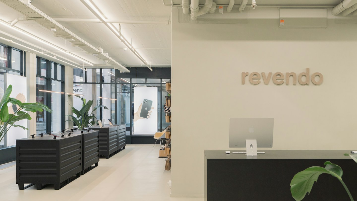 Revendo logo above reception desk with iMac computer.